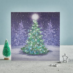 A Christmas card with an illustrated tree in a snowy forest